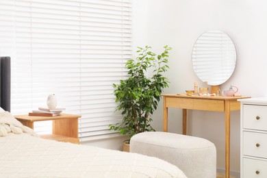 Photo of Mirror, dressing table, houseplant, bed and chest of drawers indoors. Interior design