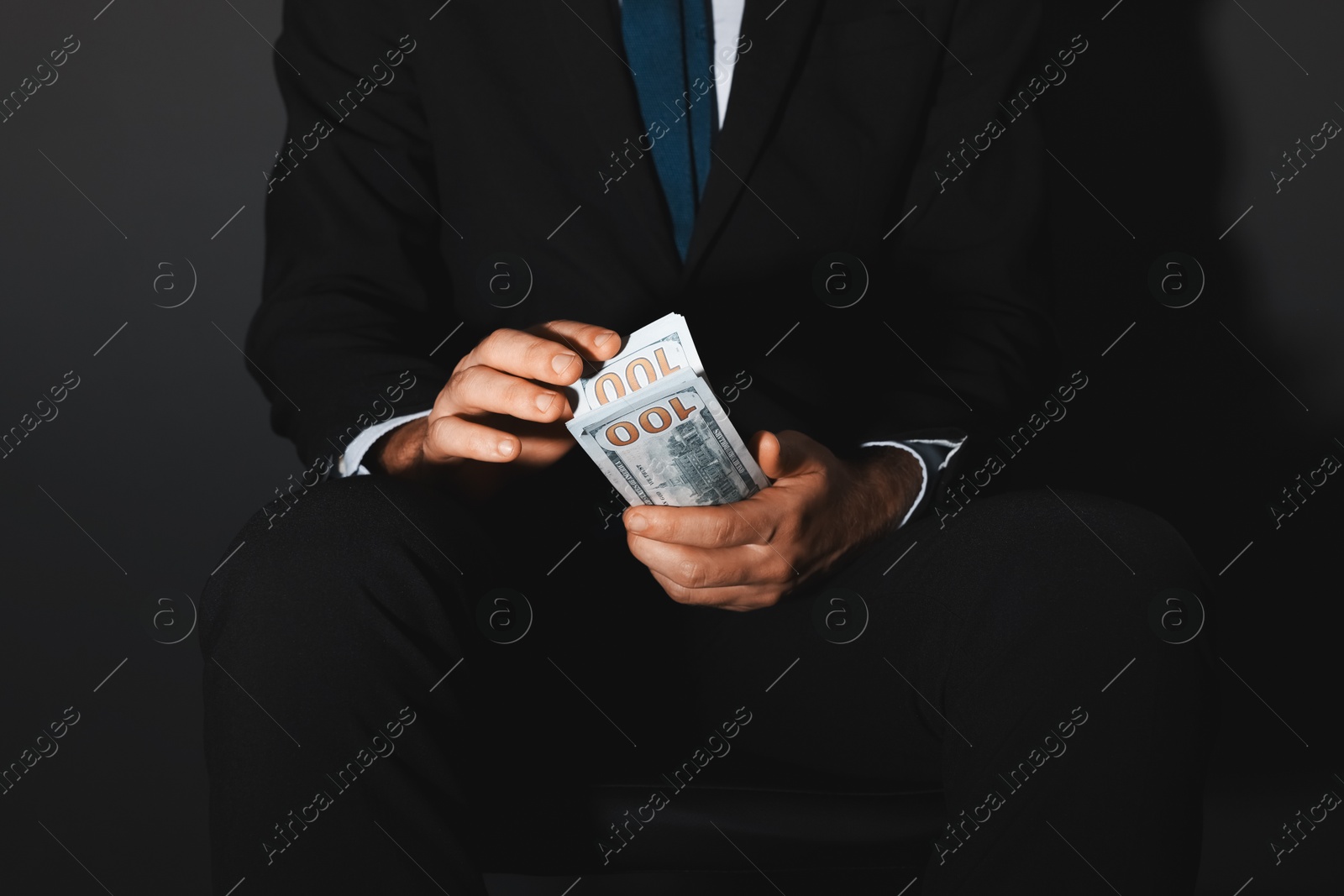 Photo of Corruption concept. Man holding dollar banknotes on black background, closeup