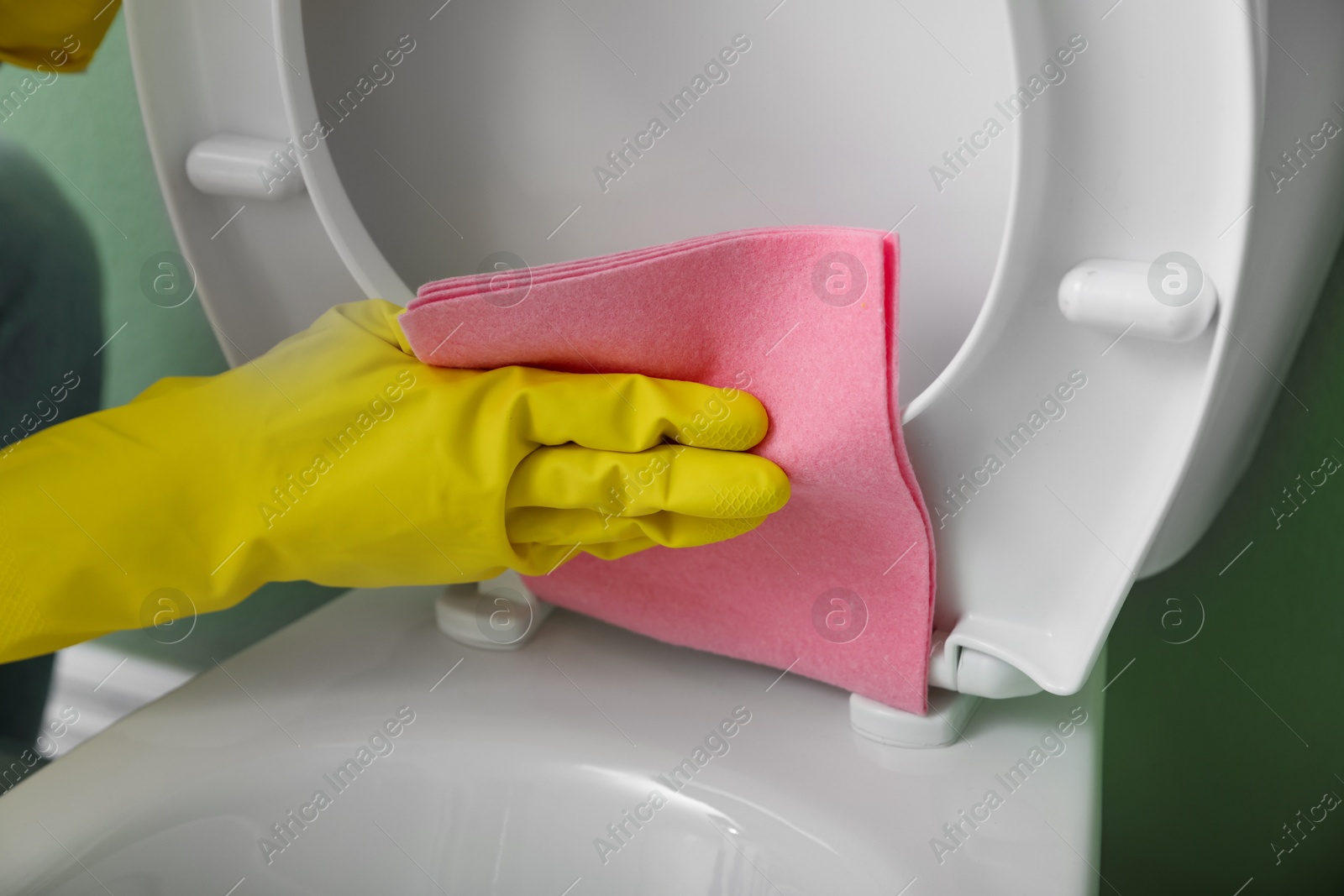 Photo of Woman cleaning toilet seat in restroom, closeup