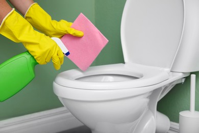 Photo of Woman cleaning toilet seat in restroom, closeup