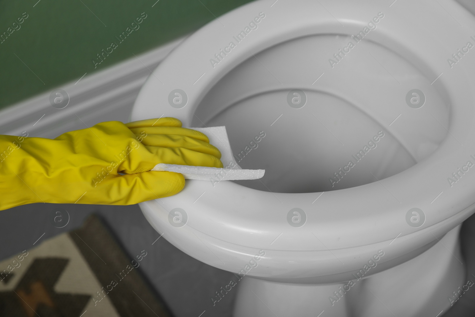 Photo of Woman wiping toilet seat in restroom, closeup