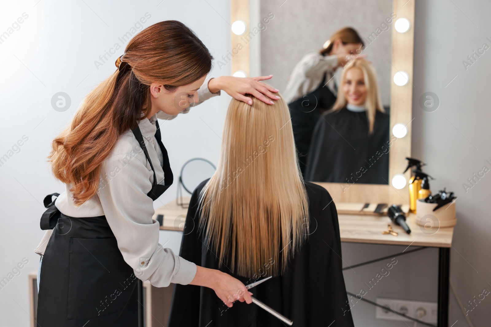 Photo of Professional hairdresser combing woman's hair in salon