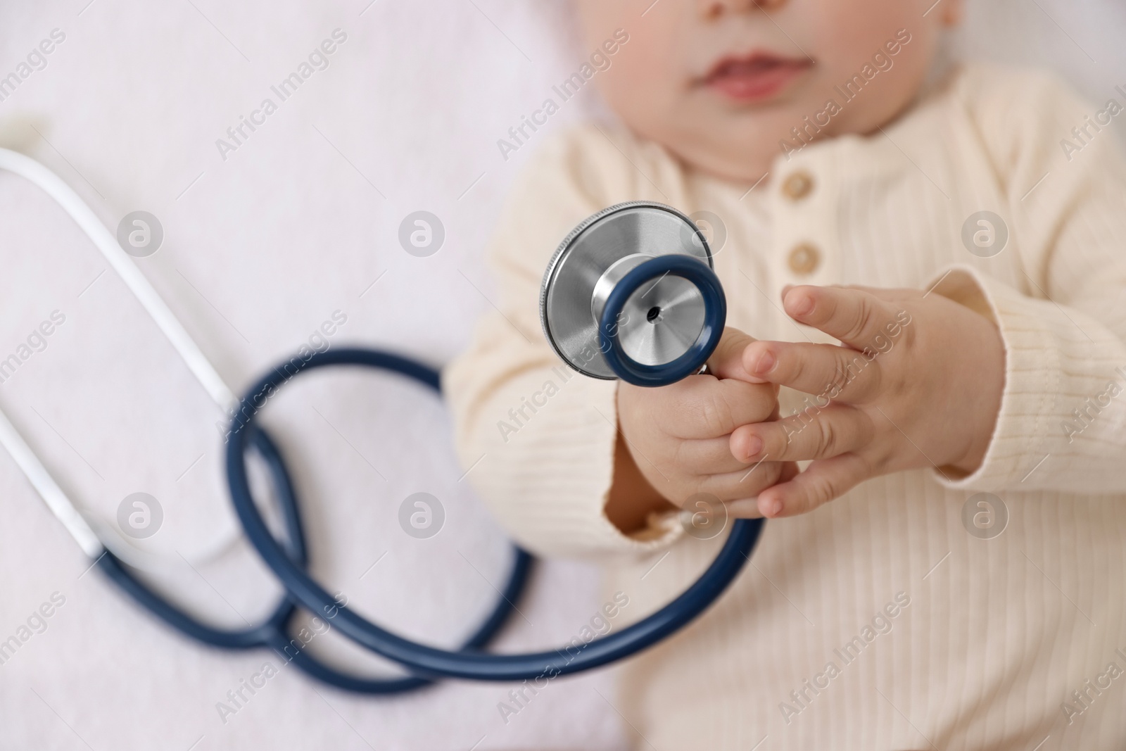 Photo of Little child with stethoscope on towel, top view. Checking baby's health