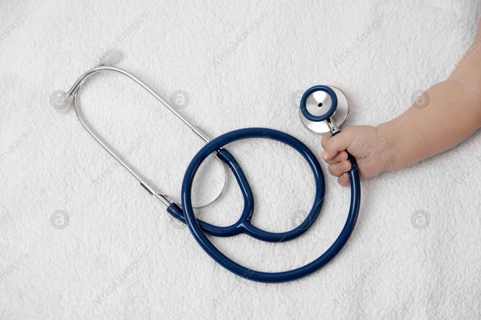 Photo of Little child with stethoscope on towel, top view. Checking baby's health