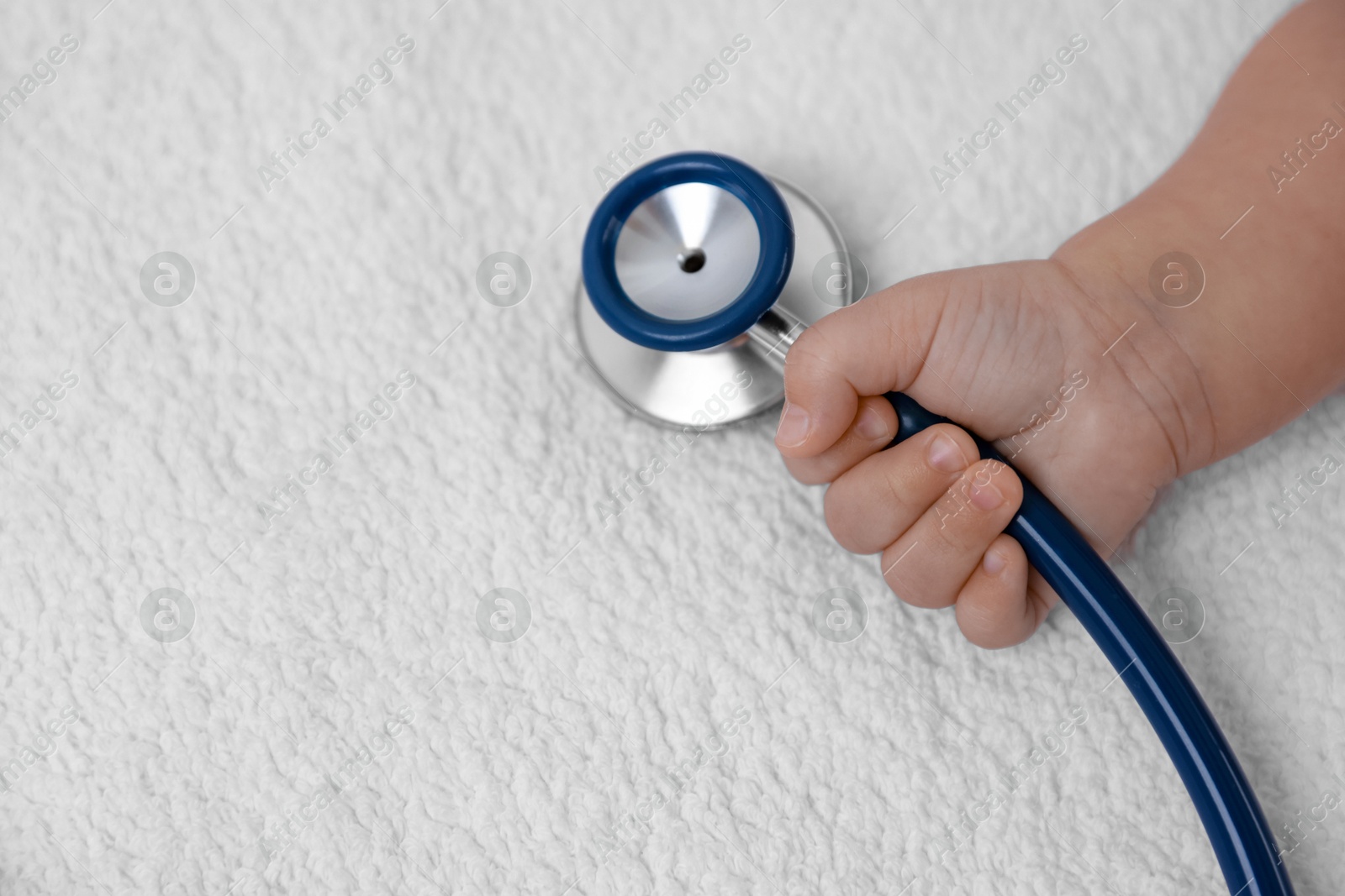 Photo of Little child with stethoscope on towel, space for text. Checking baby's health