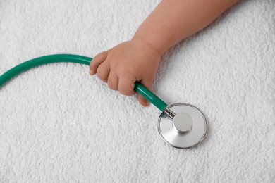 Photo of Little child with stethoscope on towel, top view. Checking baby's health