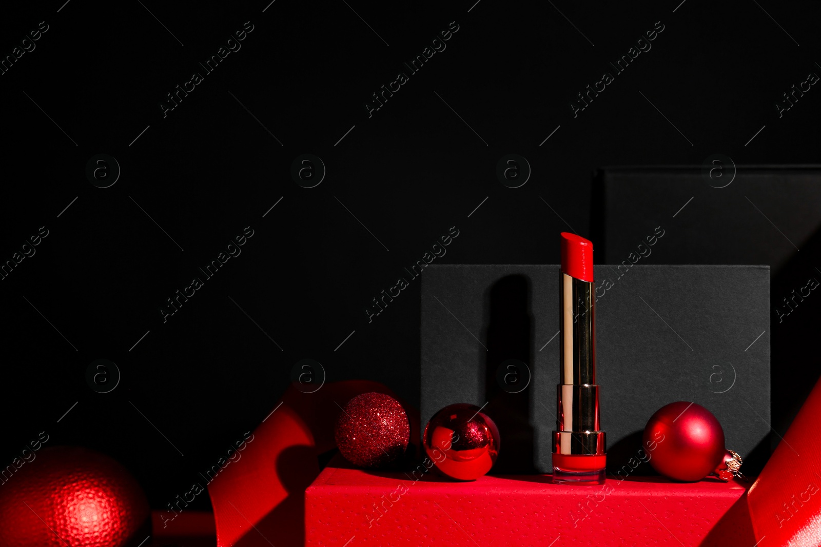 Photo of Christmas present. Red lipstick, boxes and festive decor against black background. Space for text