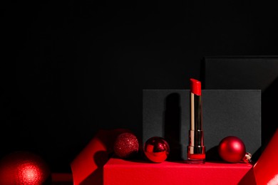 Photo of Christmas present. Red lipstick, boxes and festive decor against black background. Space for text