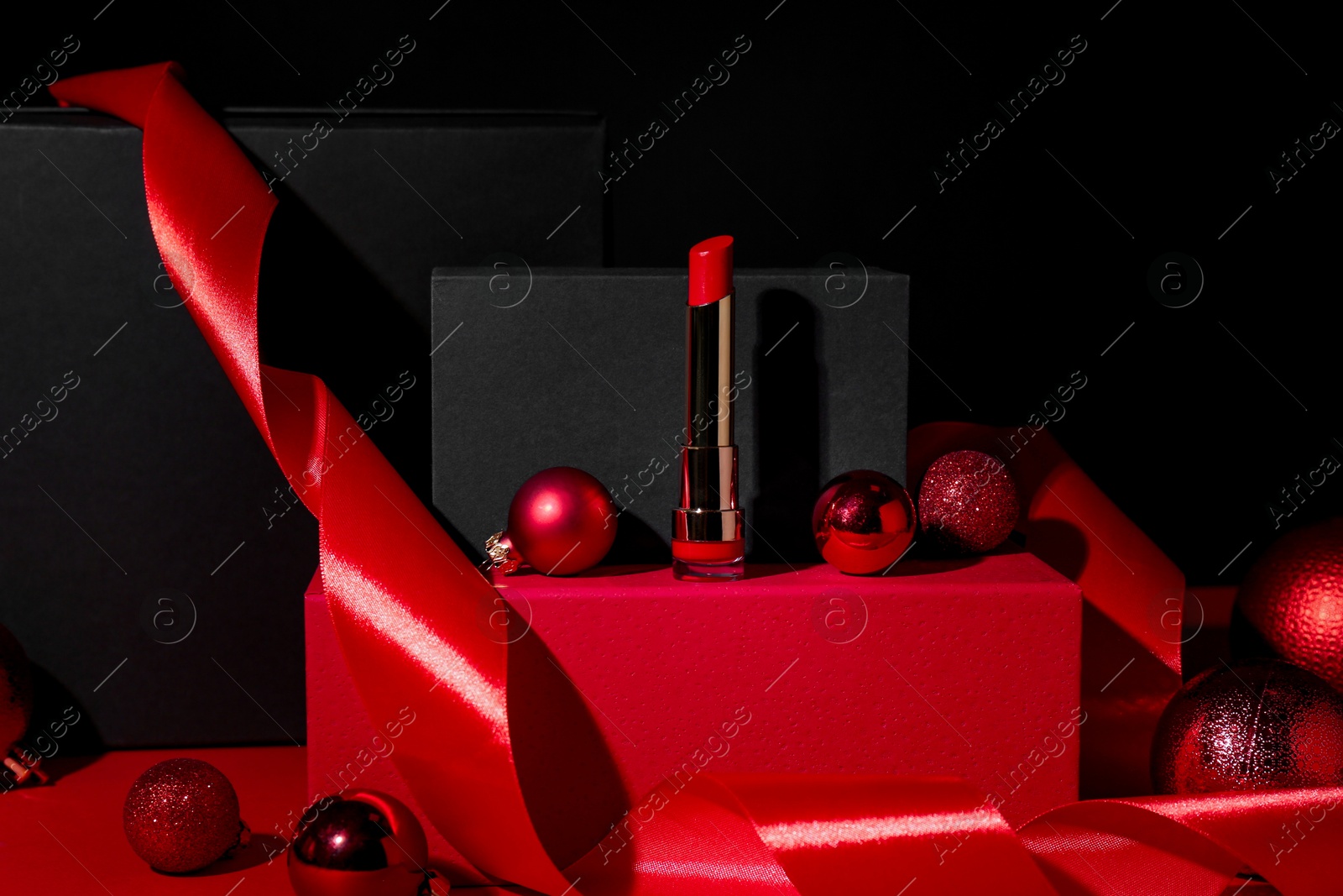 Photo of Christmas present. Red lipstick, boxes and festive decor against black background