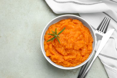 Photo of Tasty mashed sweet potato with rosemary in bowl served on grey textured table, flat lay. Space for text