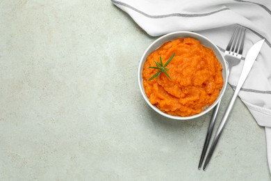 Photo of Tasty mashed sweet potato with rosemary in bowl served on grey textured table, flat lay. Space for text