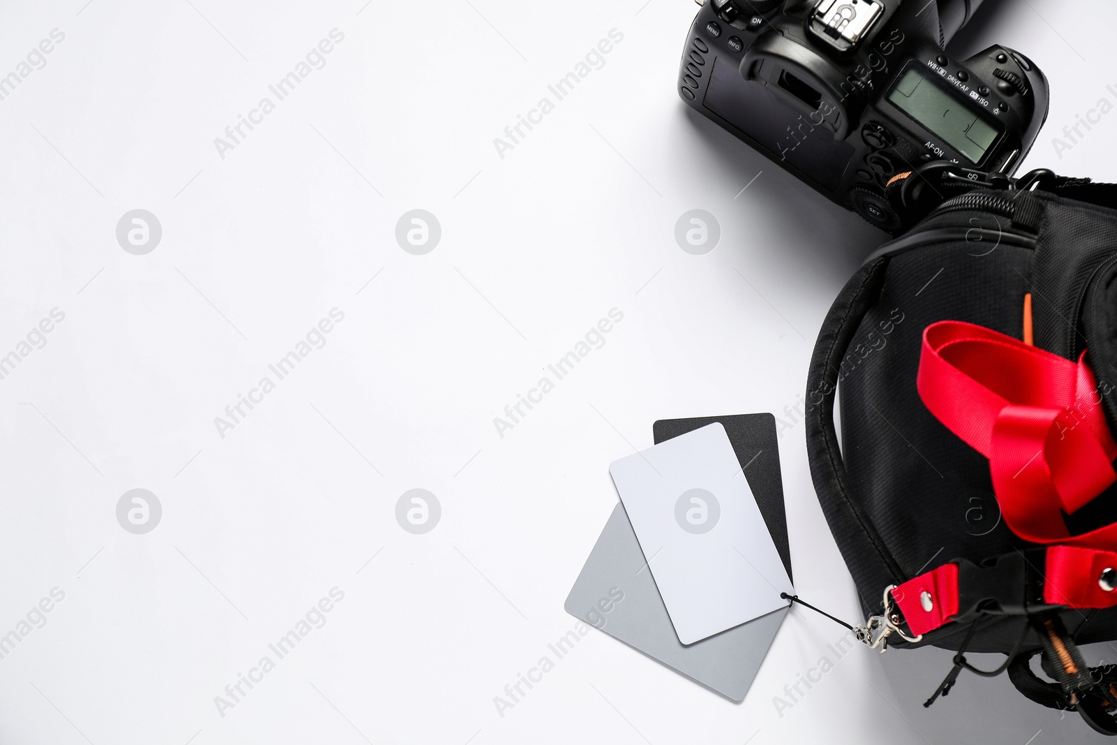 Photo of White balance calibration cards, camera and bag on white background, top view