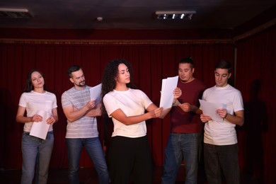 Photo of Professional actors with their scripts rehearsing in theatre