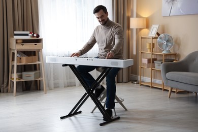 Photo of Smiling man playing synthesizer at home. Electronic musical instrument