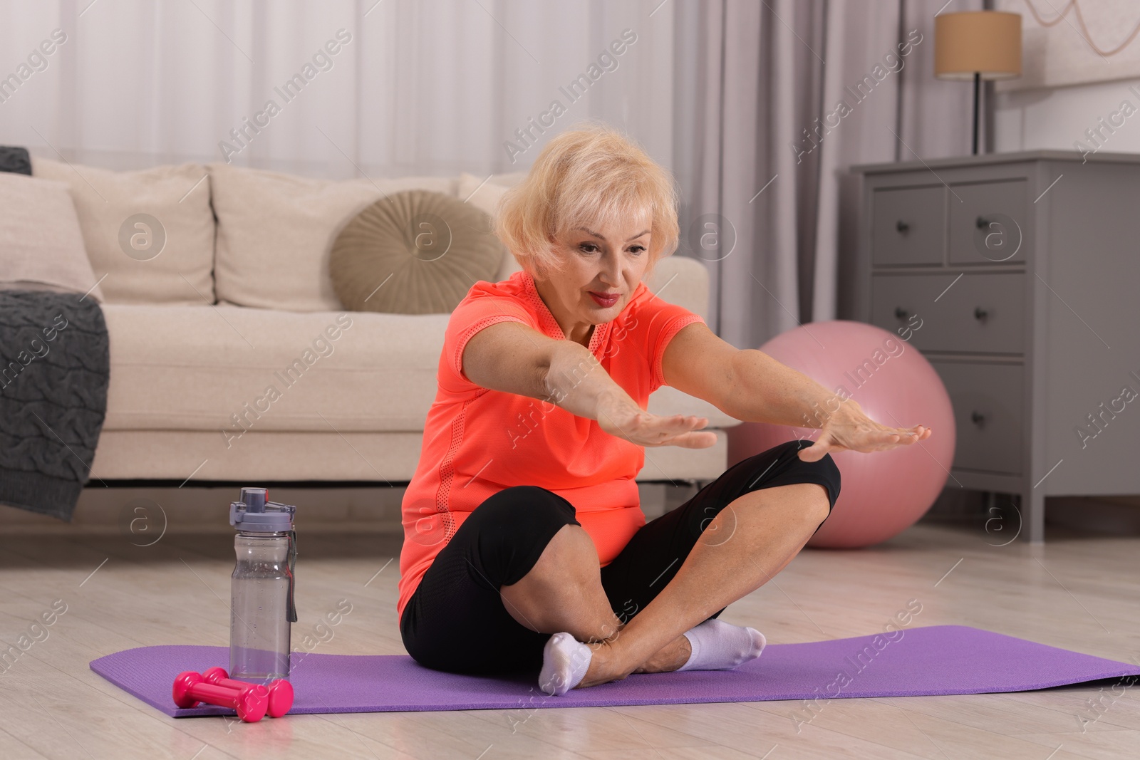 Photo of Senior woman exercising with fitness mat at home