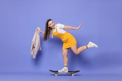 Photo of Smiling woman riding skateboard on violet background