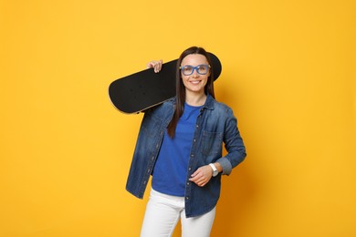 Photo of Smiling woman with skateboard on orange background