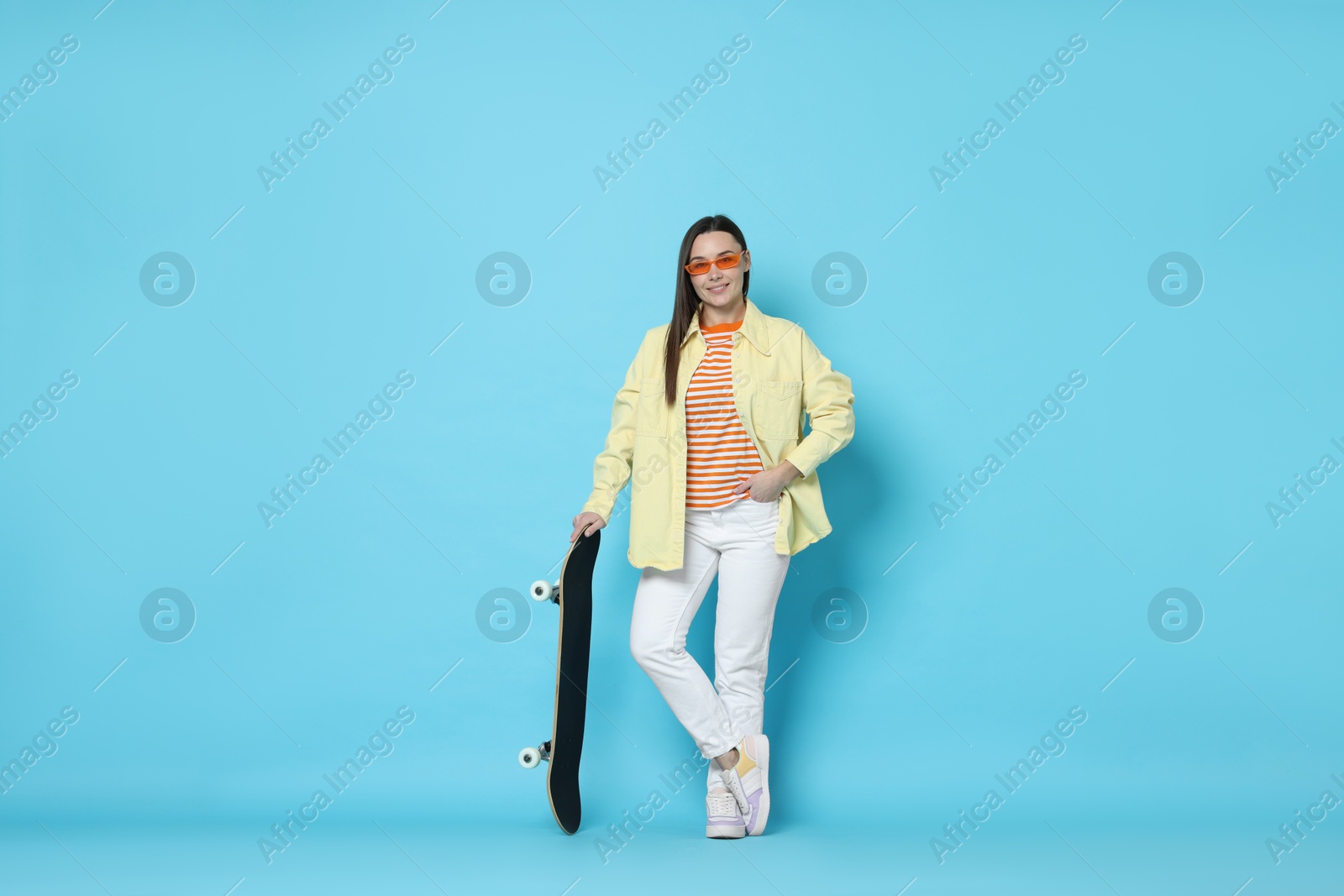 Photo of Smiling woman with skateboard on light blue background