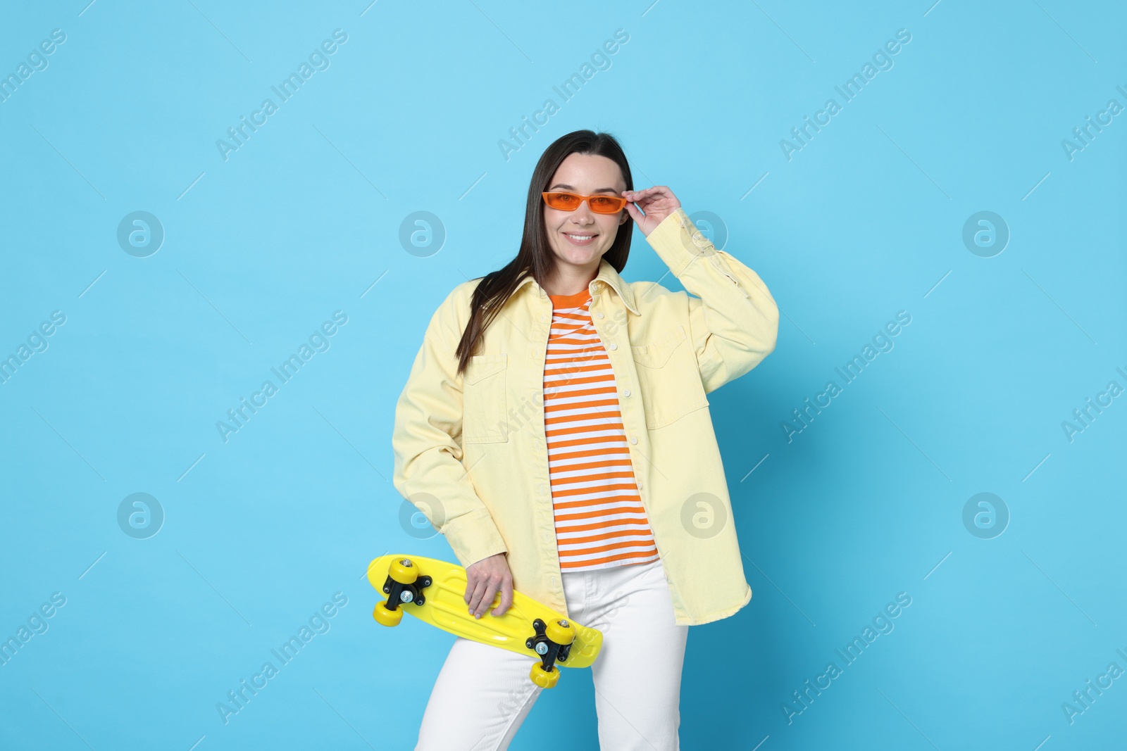 Photo of Smiling woman with penny board on light blue background