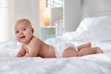 Photo of Cute little baby in diaper on bed indoors