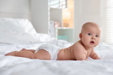 Photo of Cute little baby in diaper on bed indoors