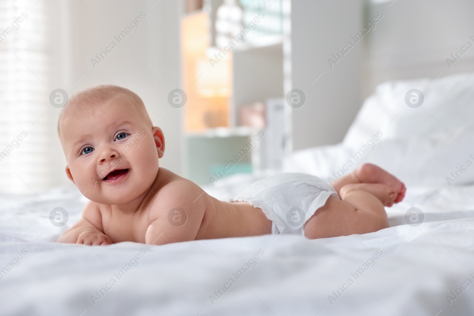 Photo of Cute little baby in diaper on bed indoors