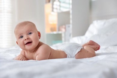 Photo of Cute little baby in diaper on bed indoors