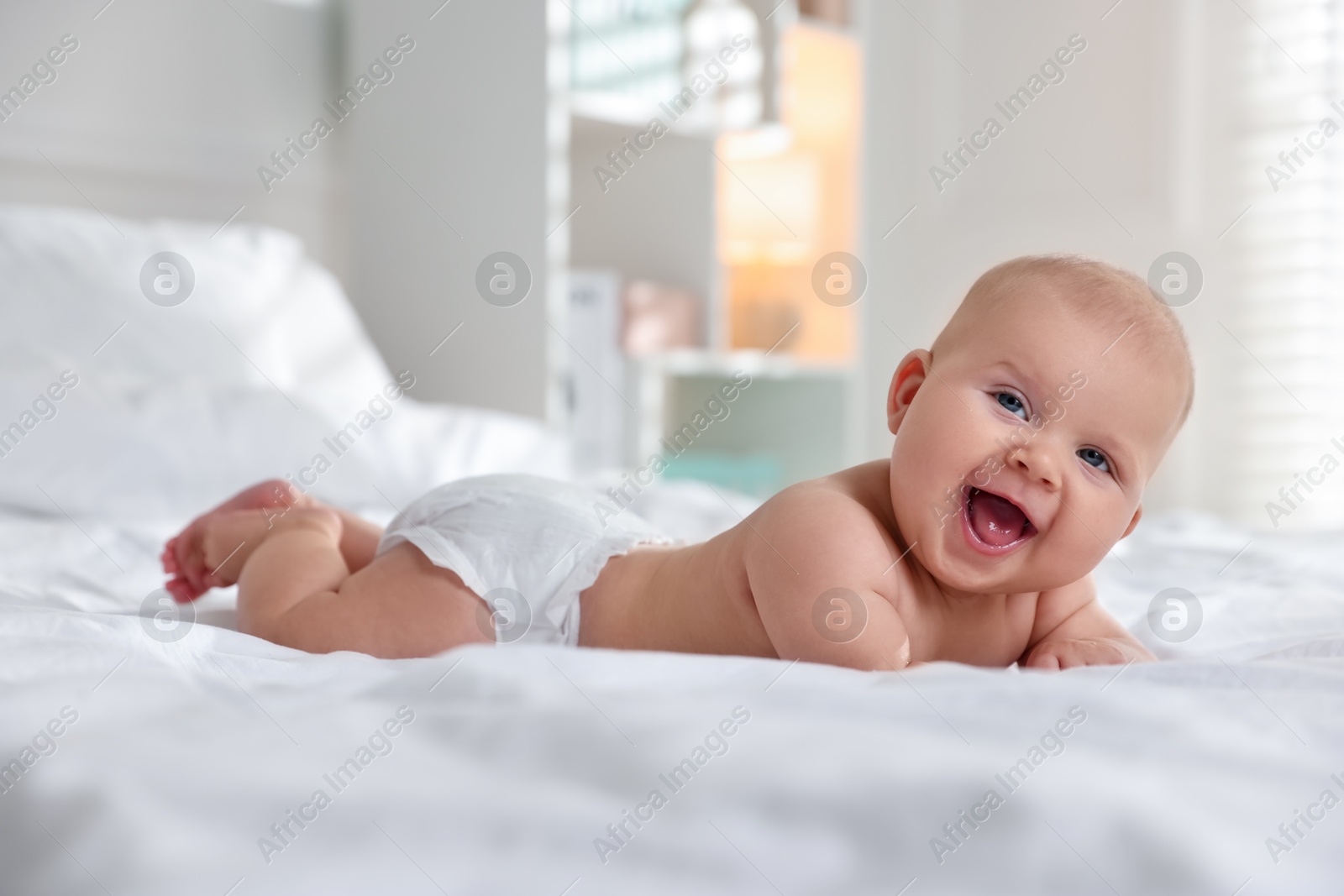 Photo of Cute little baby in diaper on bed indoors