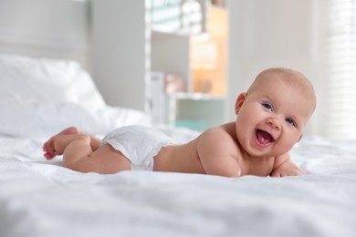 Photo of Cute little baby in diaper on bed indoors