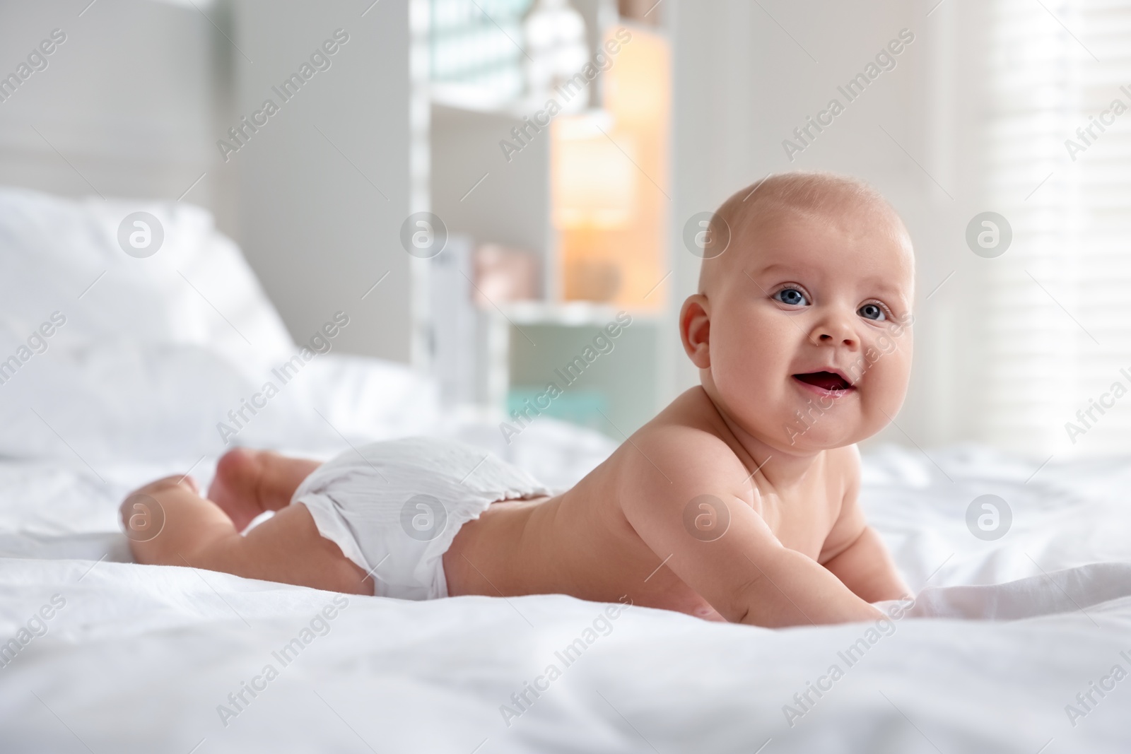 Photo of Cute little baby in diaper on bed indoors