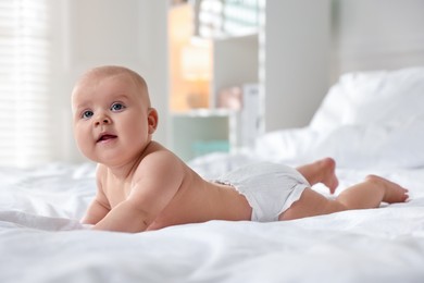 Photo of Cute little baby in diaper on bed indoors