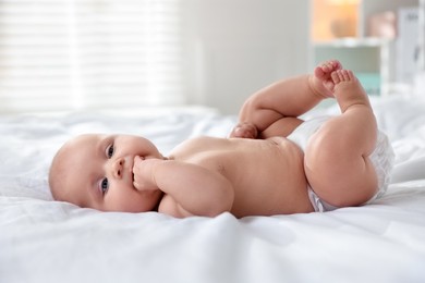 Photo of Cute little baby in diaper on bed indoors