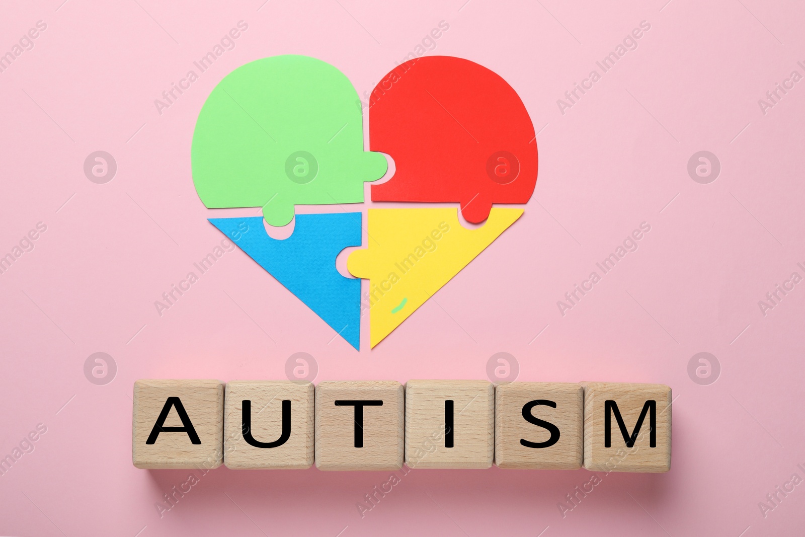 Photo of Wooden cubes with word Autism and heart made of puzzle pieces on pink background, flat lay