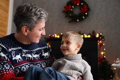 Photo of Dad and son near decorated fireplace at home. Christmas season