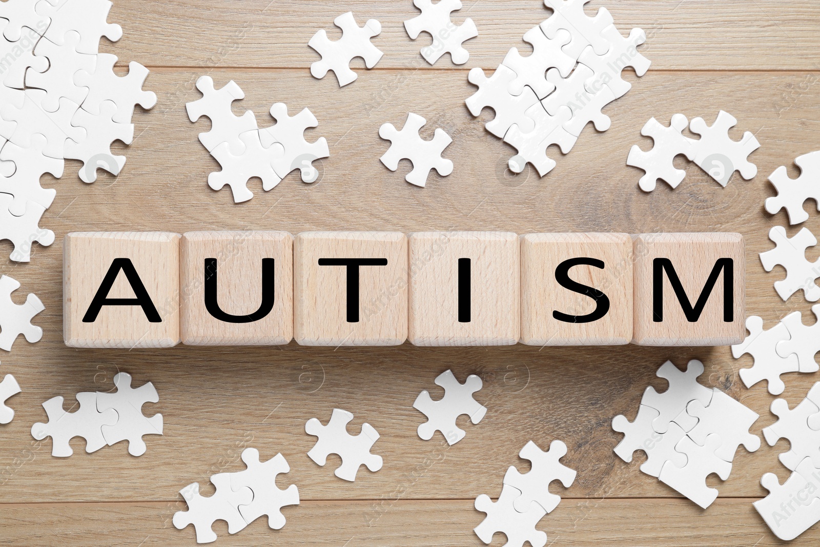 Photo of Word Autism made of cubes and puzzle pieces wooden background, flat lay