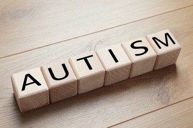 Photo of Word Autism made of cubes on wooden background