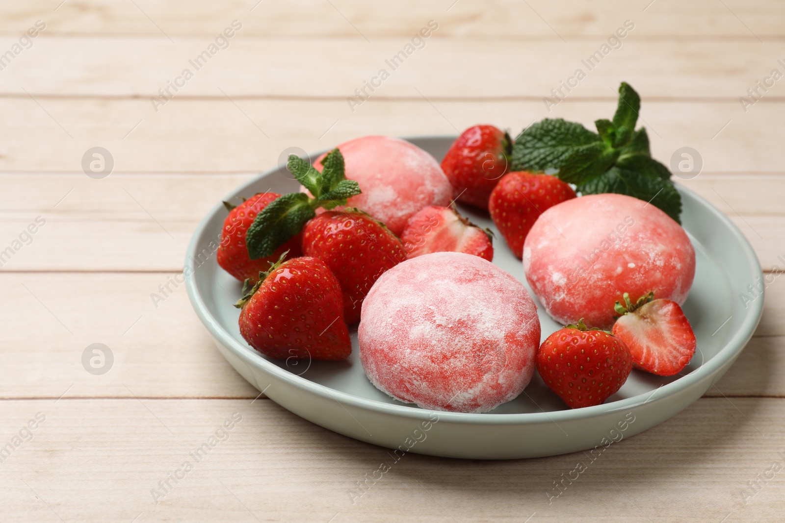 Photo of Delicious mochi, strawberries and mint on wooden table, closeup