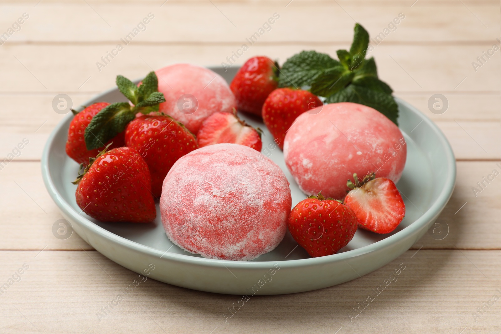 Photo of Delicious mochi, strawberries and mint on wooden table, closeup