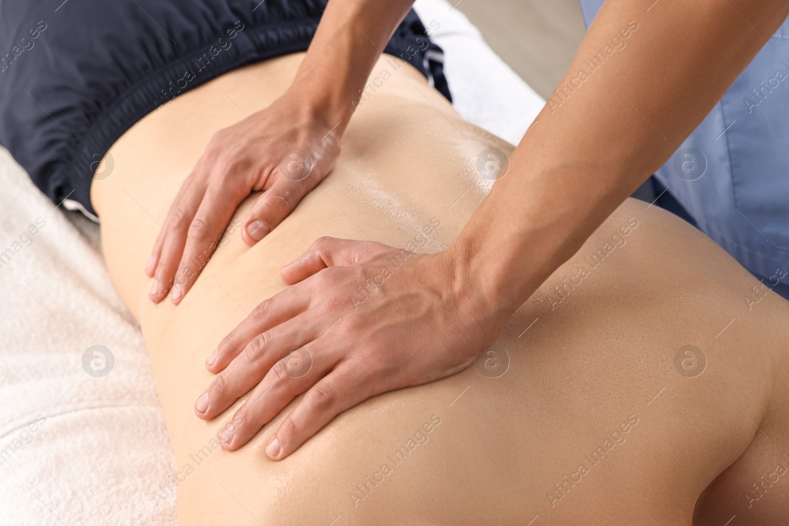 Photo of Professional physiotherapist doing back massage for his client indoors, closeup