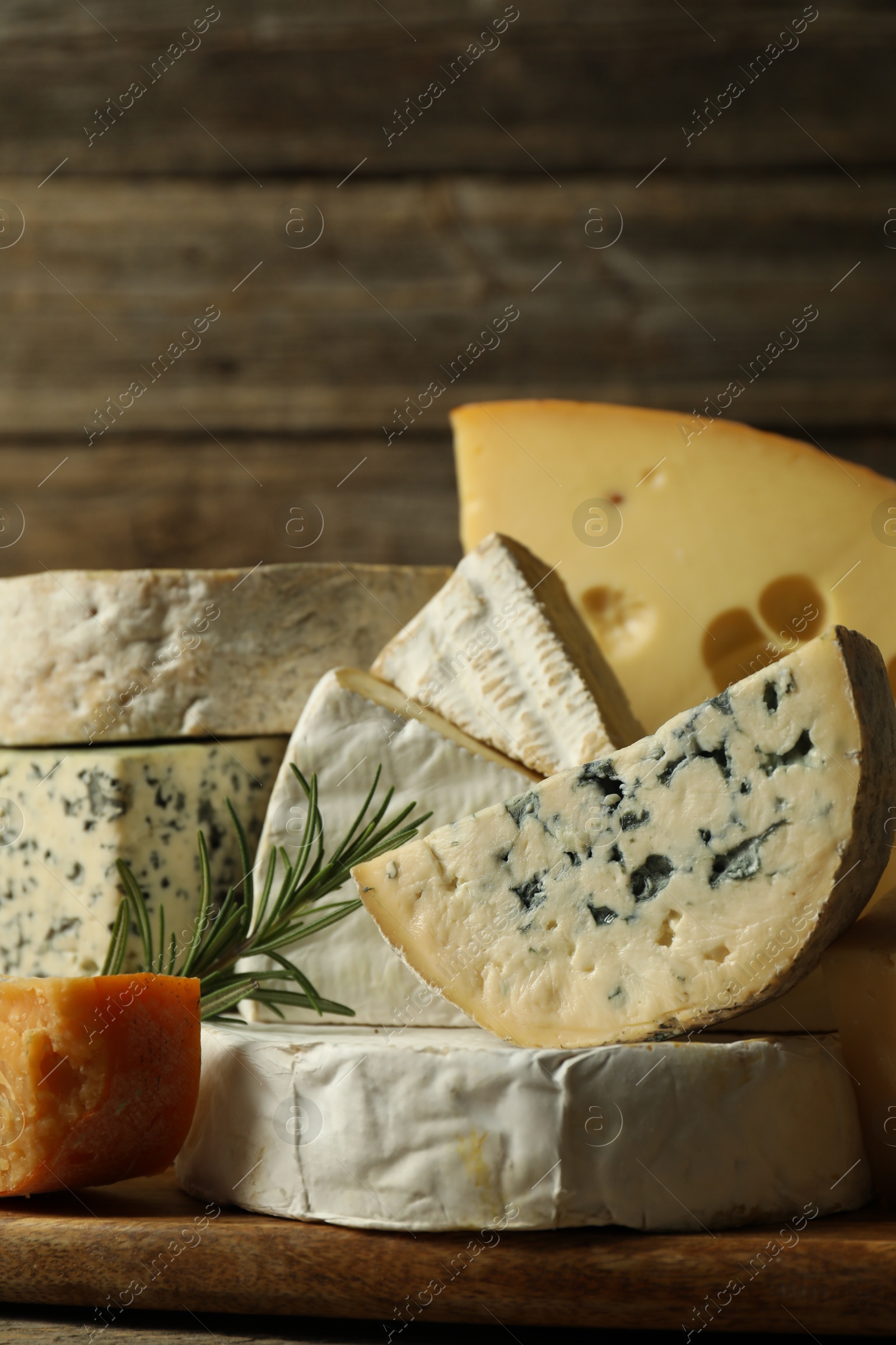 Photo of Different types of cheese and rosemary on table, closeup