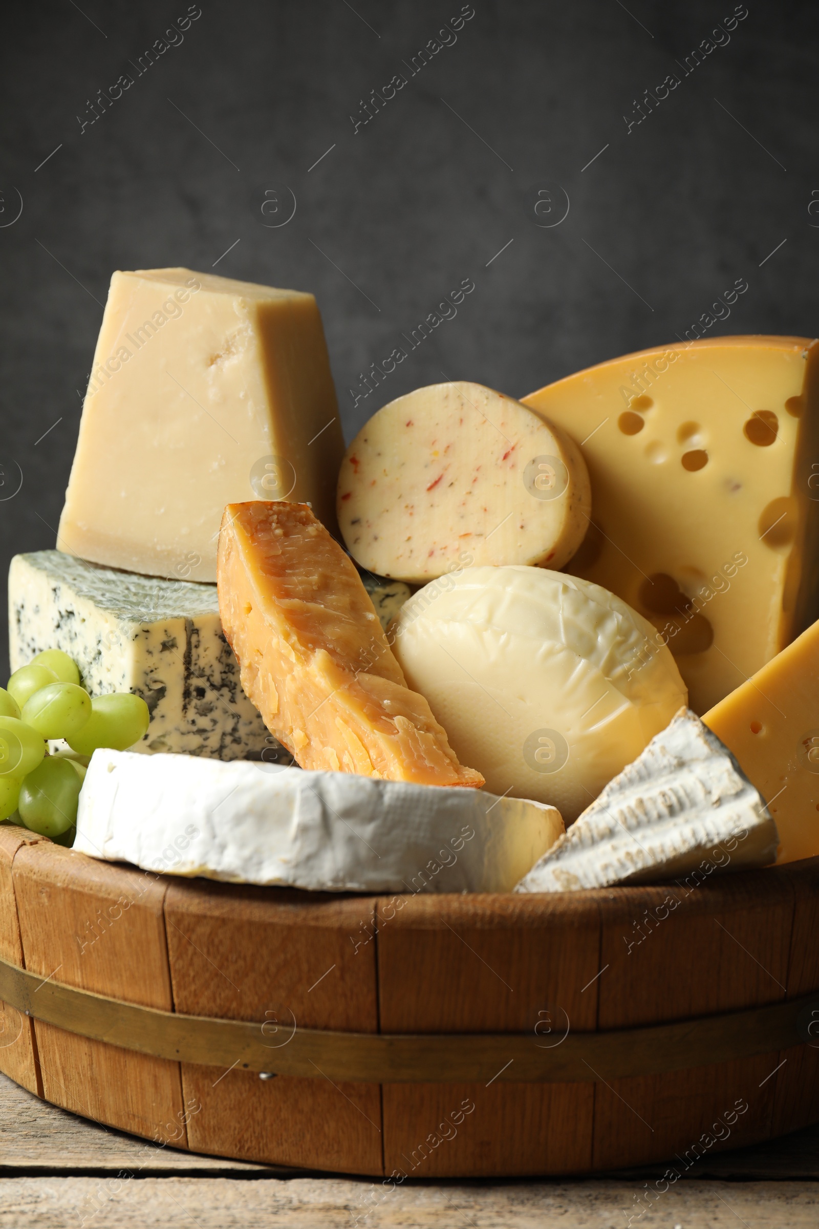 Photo of Different types of cheese and grapes on wooden table, closeup