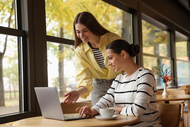 Photo of Women with laptop working together in cafe