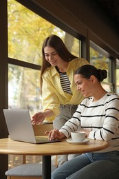 Photo of Women with laptop working together in cafe