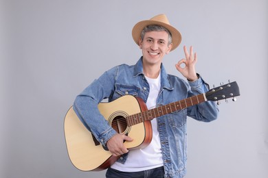 Photo of Happy man with guitar showing okay gesture on light grey background