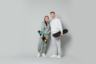 Photo of Happy friends with skateboards on light grey background