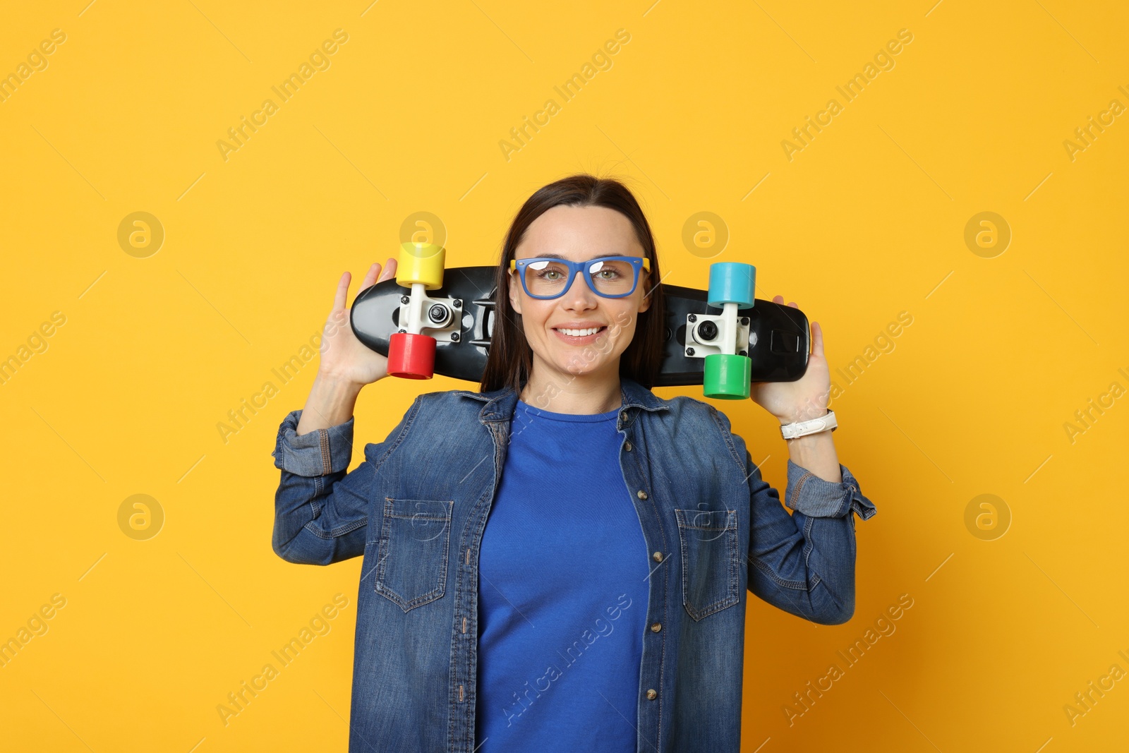 Photo of Smiling woman with penny board on orange background