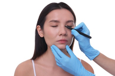 Photo of Doctor drawing marks on patient's nose for plastic surgery operation against white background, closeup