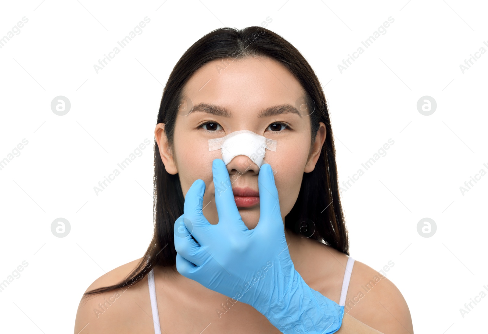 Photo of Doctor checking patient's nose after plastic surgery operation on white background, closeup