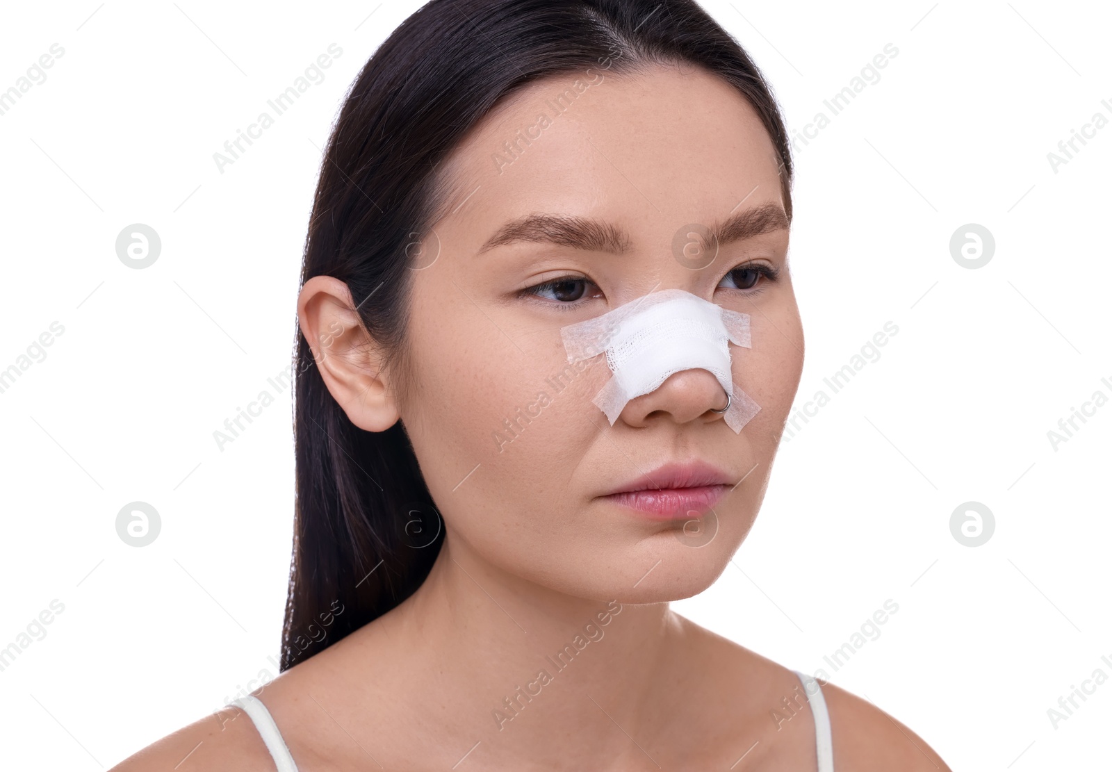 Photo of Woman with medical bandage on her nose after plastic surgery operation against white background, closeup