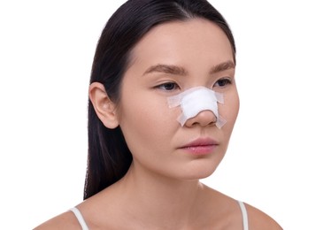 Photo of Woman with medical bandage on her nose after plastic surgery operation against white background, closeup